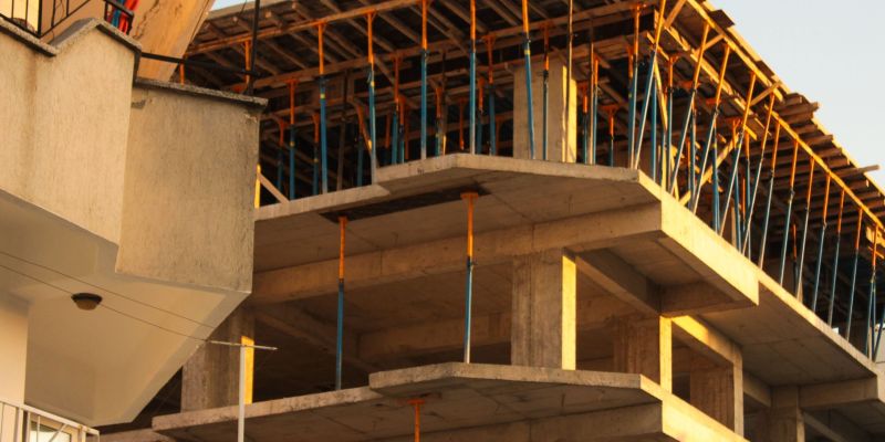 Concrete building under construction with scaffolding lit by warm sunset light.