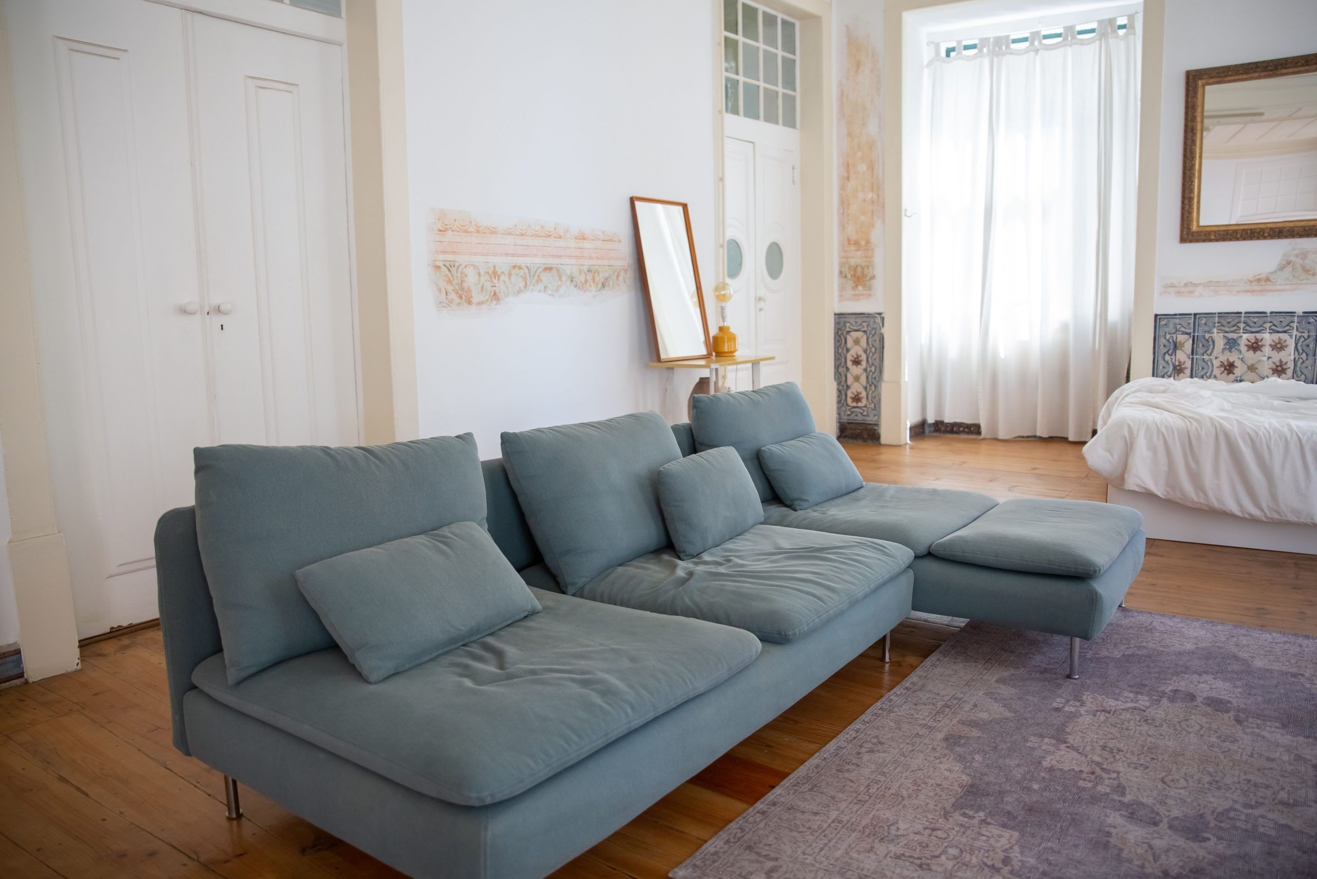 Cozy living room featuring a stylish light blue sofa, wooden floor, and natural light.