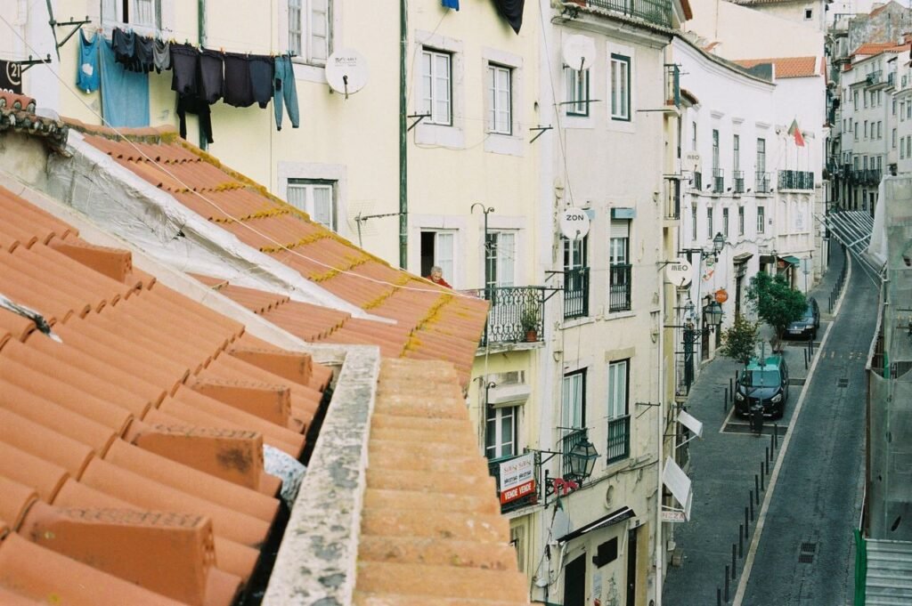 Charming Lisbon street with traditional rooftops and laundry hanging out to dry, capturing local architecture.